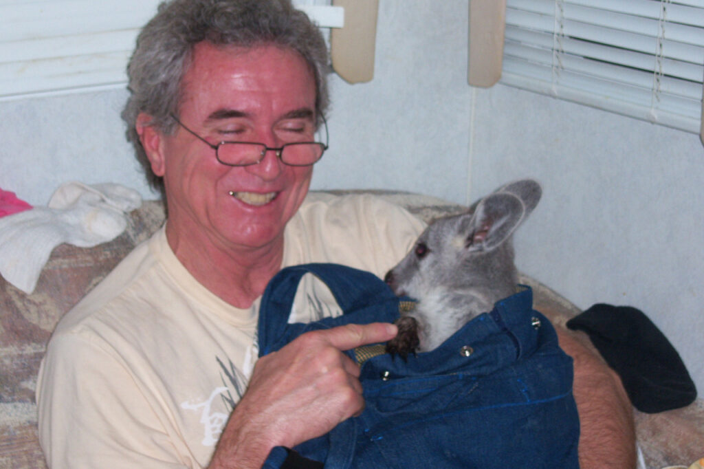 Bob holding a young joey in a denim pouch
